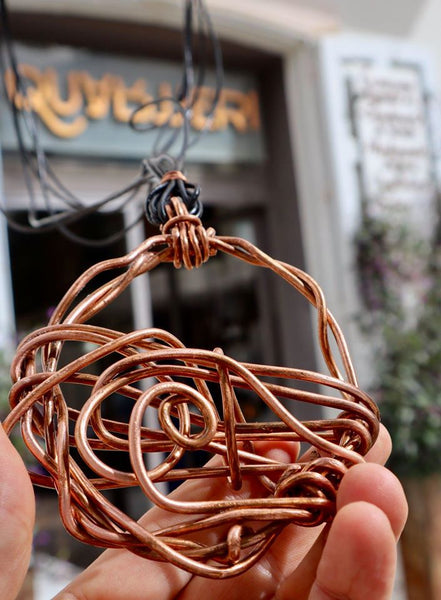 QUARTIERI Tribal: pendente tondo intrecciato su se stesso con filo di rame e cuoio nero.
