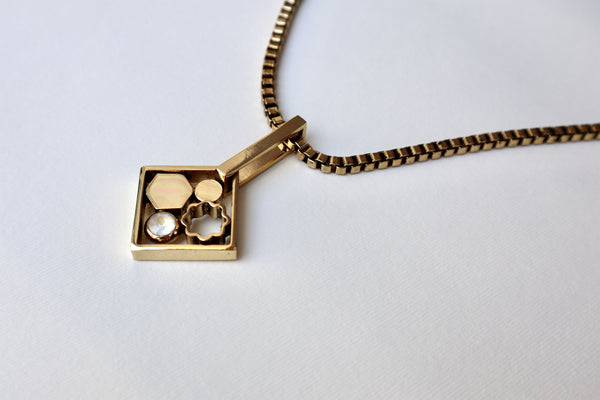Collana décolleté con catena quadrata color oro antico e pendente con motivi astratti.