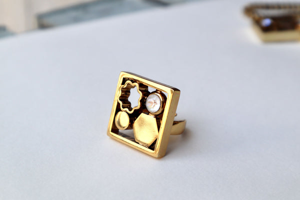 Collana décolleté con catena quadrata color oro antico e pendente con motivi astratti.